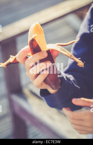 Girl's hand holding pelés banane rouge Banque D'Images