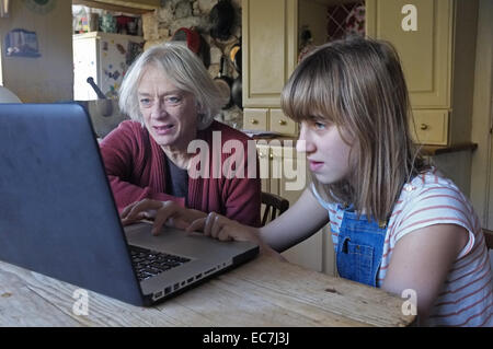 Une jeune fille de 11 ans, sa grand-mère apprend à utiliser un ordinateur Banque D'Images