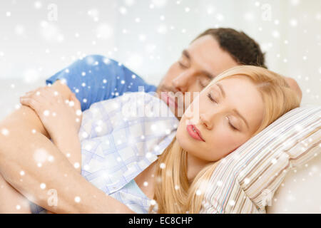 Sleeping couple lying on sofa et hugging at home Banque D'Images