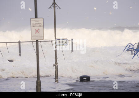 Bushmills, Irlande du Nord, Royaume-Uni. Dec 10, 2014. Vagues envahissent le parc pour enfants au Crescent Portstewart l'Irlande du Nord. L'intense tempête ou une bombe météorologique a été causée par une chute rapide de la pression (plus de 24 millibars en 24 heures). Crédit : Brian Wilkinson/Alamy Live News Banque D'Images