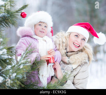 Mère de famille heureuse et kid decorating Christmas Tree outdoor Banque D'Images