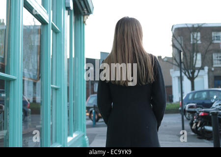 Vue arrière plan d'une jeune femme en passant devant un magasin du village. Banque D'Images