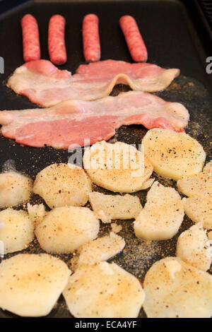 Bacon et saucisses avec des pommes de terre sur une crêpière Banque D'Images