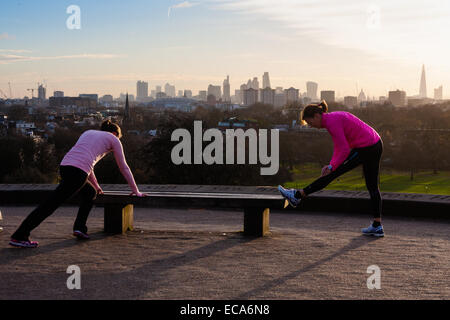 Londres, Royaume-Uni. 11 Décembre, 2014. Météo France : deux femmes faites des exercices d'étirement sur la toile de fond de l'horizon de Londres Crédit : Paul Davey/Alamy Live News Banque D'Images