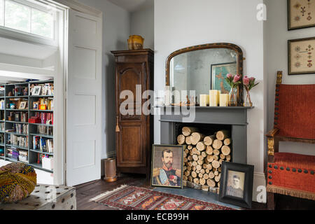 Tapis Vintage sur plancher en bois en face d'une cheminée avec des bûches et des portraits de famille Banque D'Images