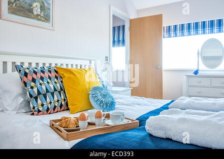 Œufs durs, des croissants et du thé pour le petit déjeuner au lit sur un plateau dans un cadre coloré, frais, Airey, ensoleillée chambre contemporain Banque D'Images