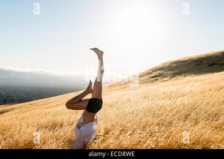 Woman performing handstand sur les collines ensoleillées Banque D'Images