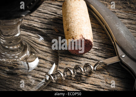 Verre à vin avec tire-bouchon et du liège sur table en bois rustique Banque D'Images