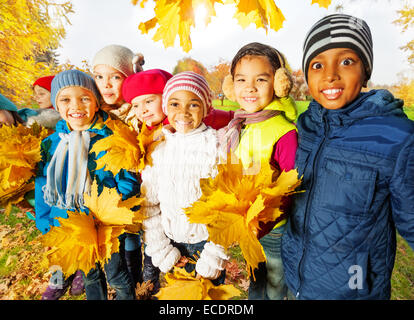 Des enfants heureux avec des tas de feuilles d'érable jaune Banque D'Images