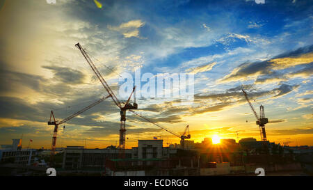 Paysage industriel avec des silhouettes de grues sur le coucher du soleil ba Banque D'Images