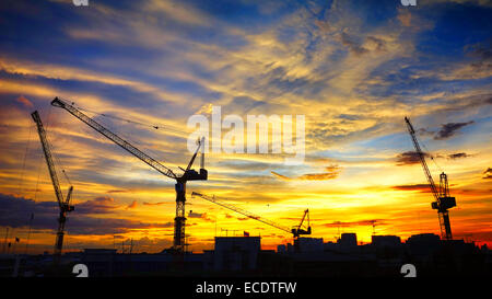 Paysage industriel avec des silhouettes de grues sur le coucher du soleil ba Banque D'Images