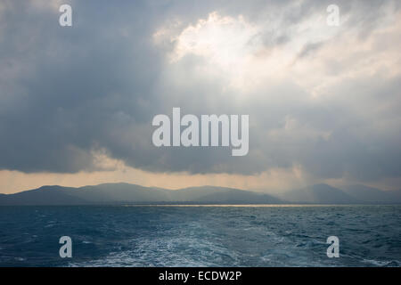 Rayons à travers le trou dans les nuages au-dessus de l'océan, et silhouette de vallonné Koh Samui, Thaïlande Banque D'Images