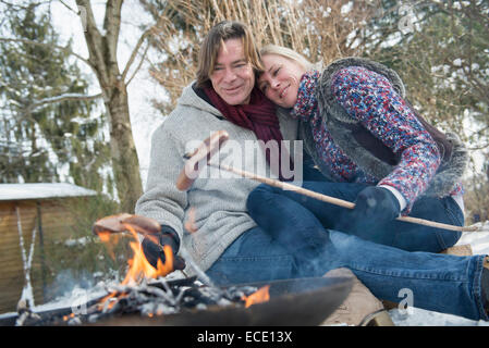 Saucisse barbecueing couple sur feu de camp Banque D'Images