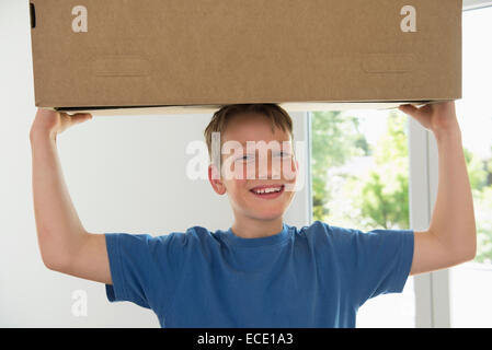 Young boy carrying box appartement neuf Banque D'Images