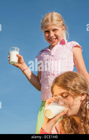 Deux jeunes filles (10-11) (12-13) dans la zone holding verre de lait, smiling, portrait, close-up Banque D'Images