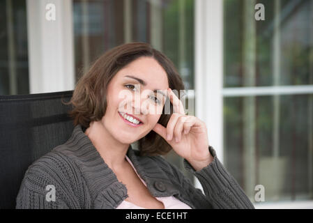 Young woman smiling sitting terrasse heureux Banque D'Images