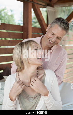 Couple marié smiling woman putting sur necklace Banque D'Images