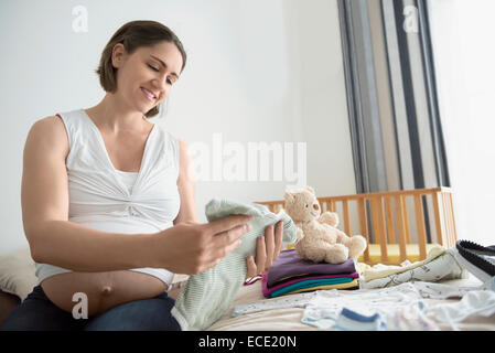 Pregnant woman holding l'emballage vêtements de bébé Banque D'Images