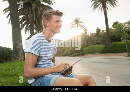 Teenage boy holding tablet computer smiling Banque D'Images