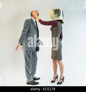 homme d'affaires se faisant gifler par femme d'affaires portant un masque Banque D'Images