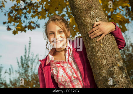 Girl holding tronc d'arbre, smiling, portrait Banque D'Images