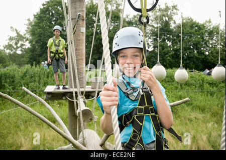 Portrait of boy climbing crag tandis qu'un autre garçon en arrière-plan, smiling Banque D'Images