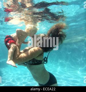 Mère embrassant bébé garçon sous l'eau dans une piscine