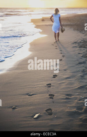 Belle femme marchant sur la plage avec ses empreintes de retour Banque D'Images