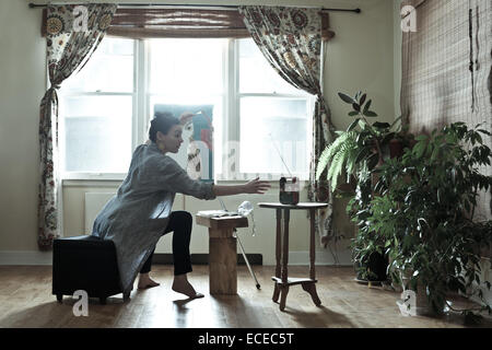 Une femme ayant atteint pour la radio pendant le dessin Banque D'Images