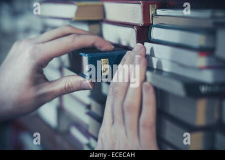 Woman taking a book from shelf Banque D'Images