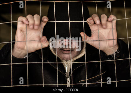 Portrait d'un homme coincé derrière une clôture métallique Banque D'Images