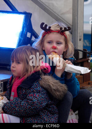 Young Girl eating a rouleau de saucisse au festival de Noël de Padstow, Cornwall, UK Banque D'Images