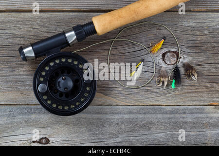 Close up of a fly reel, avec la ligne et un assortiment de mouches, et le liège traité partiel sur poteau en bois rustique Banque D'Images