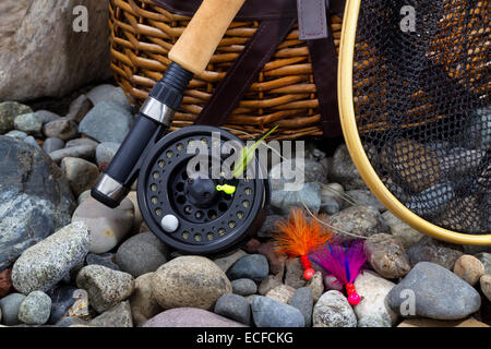 Close up de pêche de mouche moulinet, épuisette, creel et vole sur lit de rivière à sec rocks Banque D'Images