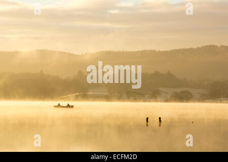 Lever du soleil sur les hommes dans un bateau de pêche sur le lac Windermere à Ambleside, Lake District, UK. Banque D'Images