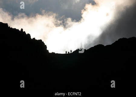 Silhouette de trois promeneurs marchant sur Edge, crête de montagne Helvellyn, Lake District, Cumbria, England, UK Banque D'Images