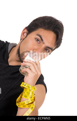 Beau jeune homme athlétique enroulé autour d'un ruban à mesurer, de boire dans un verre de lait Banque D'Images