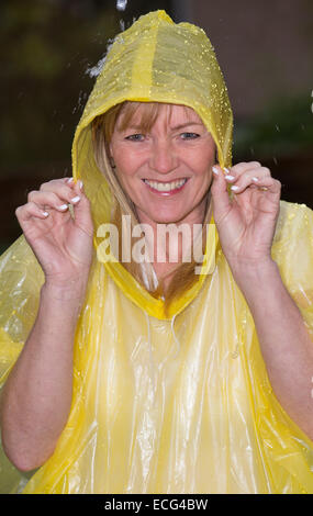 Femme en riant vêtu d'un poncho en plastique lors d'une douche de pluie Banque D'Images