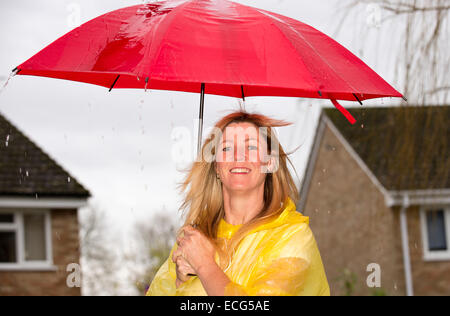 Femme tenant son parapluie ouvert rouge lors d'une forte averse de pluie Banque D'Images