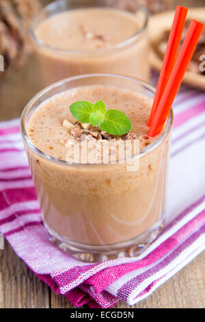 Milkshake banane et chocolat (smoothie) dans du verre avec la menthe et les noix, les produits laitiers ou dessert maison petit-déjeuner vertical Banque D'Images