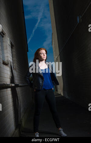 Une Rousse aux cheveux solo moody gingembre jeune femme fille ado seul) par elle-même à l'extérieur d'un bloc d'appartements abandonnés abandonnés UK Banque D'Images