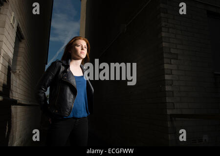 Une Rousse aux cheveux solo moody gingembre jeune femme fille ado seul) par elle-même à l'extérieur d'un bloc d'appartements abandonnés abandonnés UK Banque D'Images