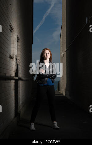 Une Rousse aux cheveux solo moody gingembre jeune femme fille ado seul) par elle-même à l'extérieur d'un bloc d'appartements abandonnés abandonnés UK Banque D'Images