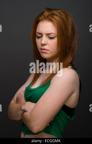 Un défi aux cheveux introvertie moody gingembre rousseur écorchés 1617 18 ans slim shadow of british girl portant un gilet vert UK Banque D'Images