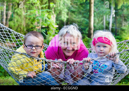 Les enfants avec grand-mère se balançant dans un hamac, close-up Banque D'Images