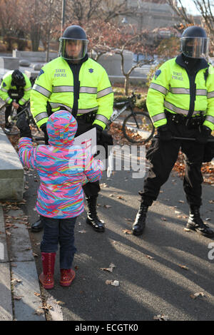 Boston, Massachusetts, USA. 13 Décembre, 2014. Un enfant marche jusqu'à une ligne de Massachusetts State Police près de la rue Nashua Prison, où les manifestants se sont réunis pendant les millions Mars rassemblement à Boston, Massachusetts, USA. La protestation, comme ceux d'autres villes aux États-Unis en ce jour, est en réponse aux récentes décisions du grand jury de ne pas inculper les policiers qui ont tué les hommes noirs non armés Michael Brown et Eric Garner, et pour les problèmes de longue date le racisme et la brutalité policière. Crédit : Susan Pease/Alamy Live News Banque D'Images