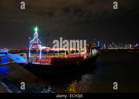 Un bateau traditionnel de dhow qui sert un bateau d'excursion décoré et éclairé avec des lumières amarrées le long de la promenade du front de mer dans la baie de Doha Qatar Banque D'Images