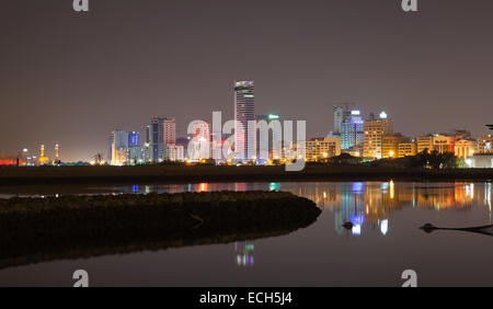 Nuit sur les toits de la ville, à l'éclat des lumières et des reflets dans l'eau. Manama, la capitale du Royaume de Bahreïn, au Moyen-Orient Banque D'Images