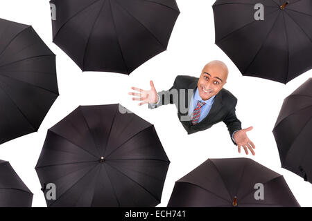 Businessman standing parmi les parapluies noir en blanc isolé Banque D'Images