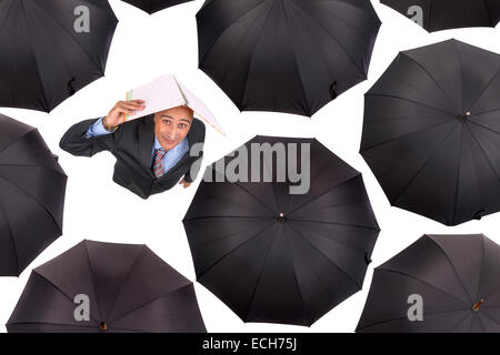 Businessman standing parmi les parapluies noir en blanc isolé Banque D'Images